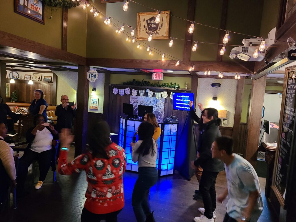 People sing with the karaoke dj and dance at the Golden Road Brewery Christmas party with a photo booth