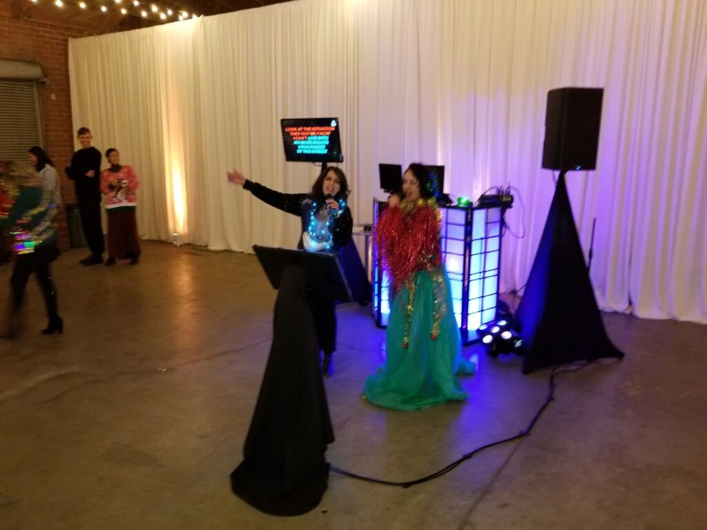 Two people singing with our karaoke dj party package with flat screen lyric displays, microphones and DJ equipment .