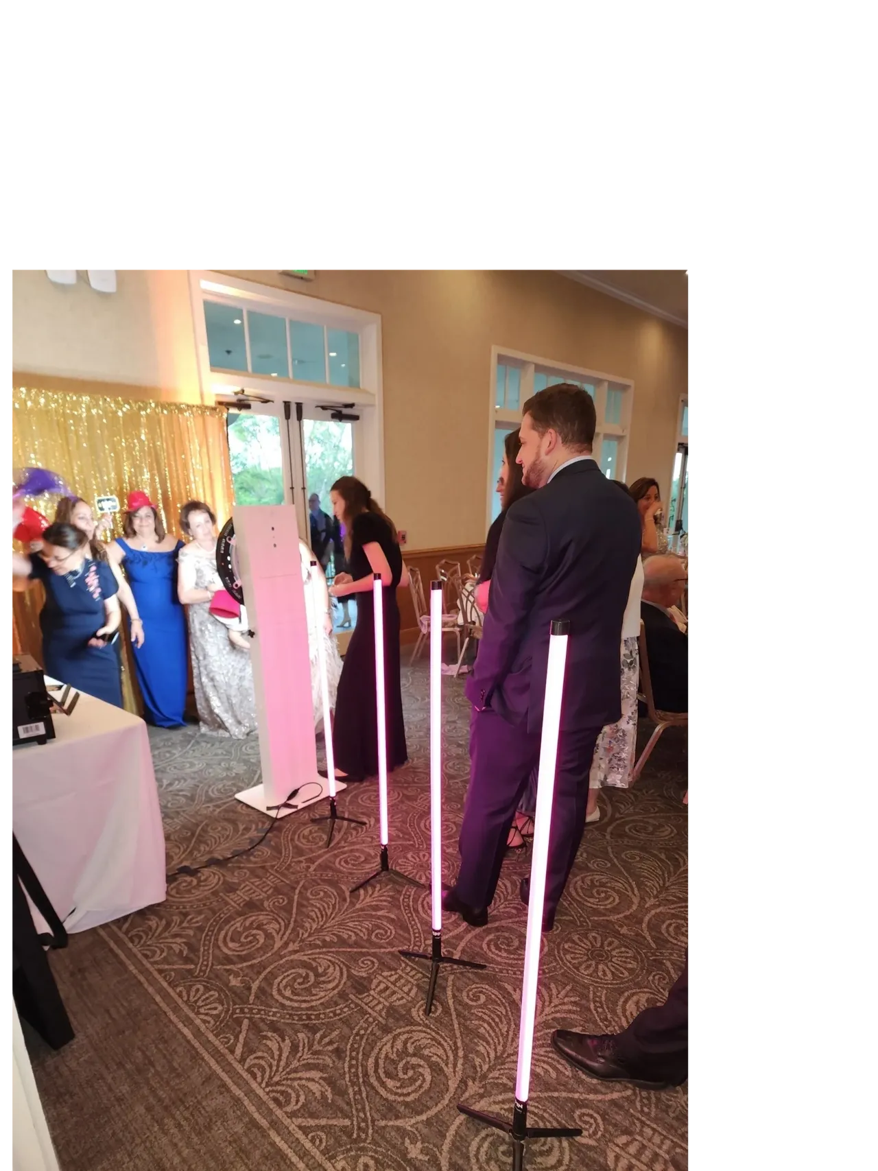 Mr Dj Services working with guests dressed formally with our photo booth attendant with pink lights, a gold sequin backdrop and props