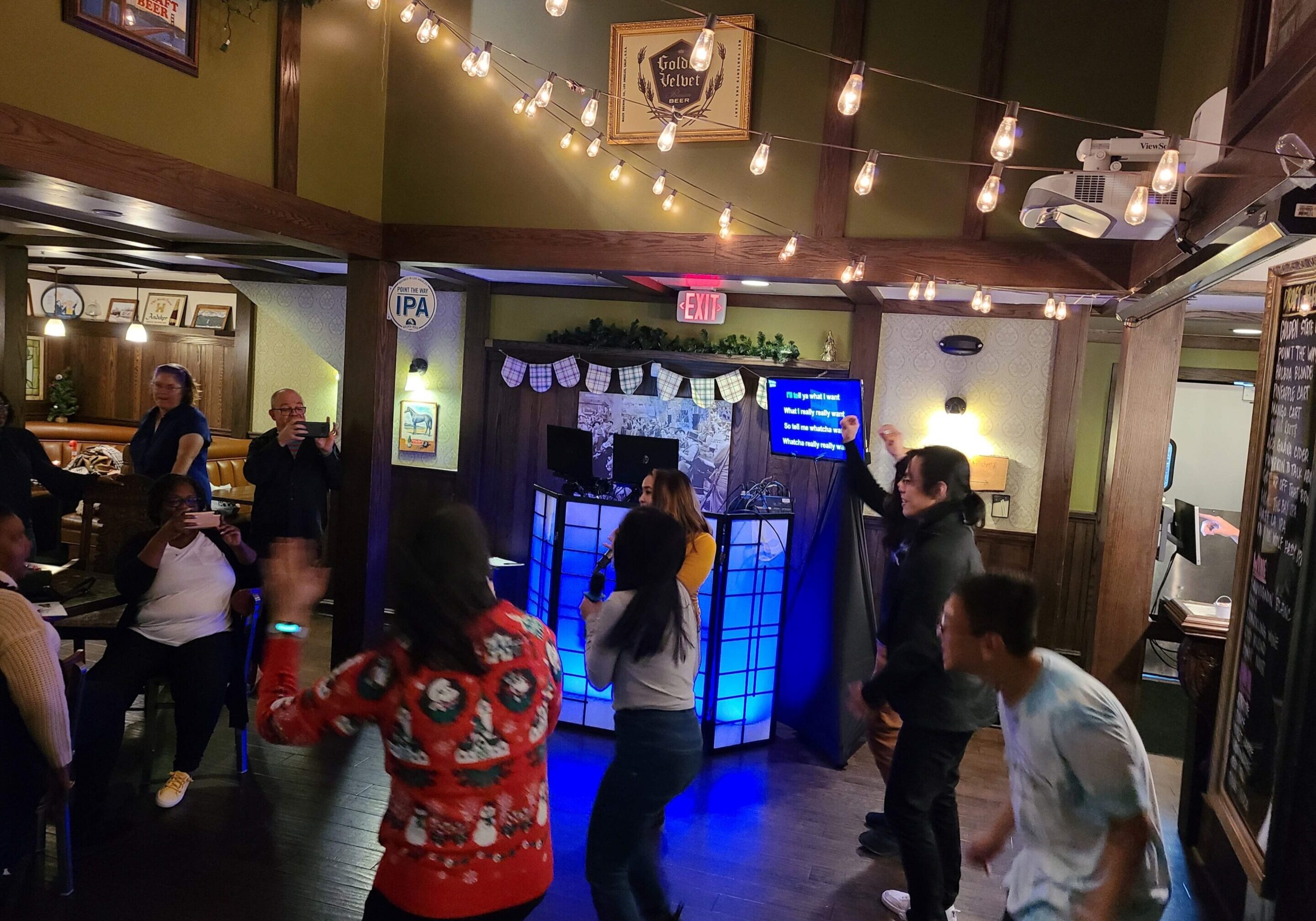 People sing with the karaoke dj and dance at the Golden Road Brewery Christmas party with a photo booth
