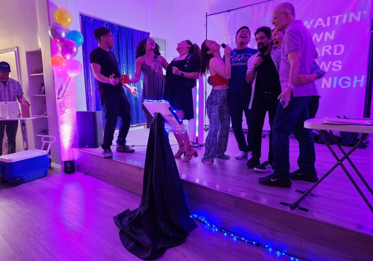 Client and guests sing together using karaoke dj package with up lights and party dj music for a birthday splash.
